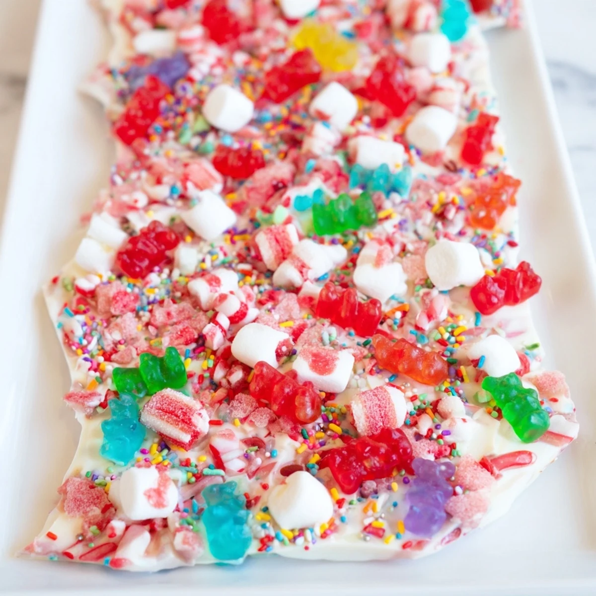 Colorful Sweet Treats: Gummy bears and candy canes scattered on shining, white chocolate, ready to enjoy.
