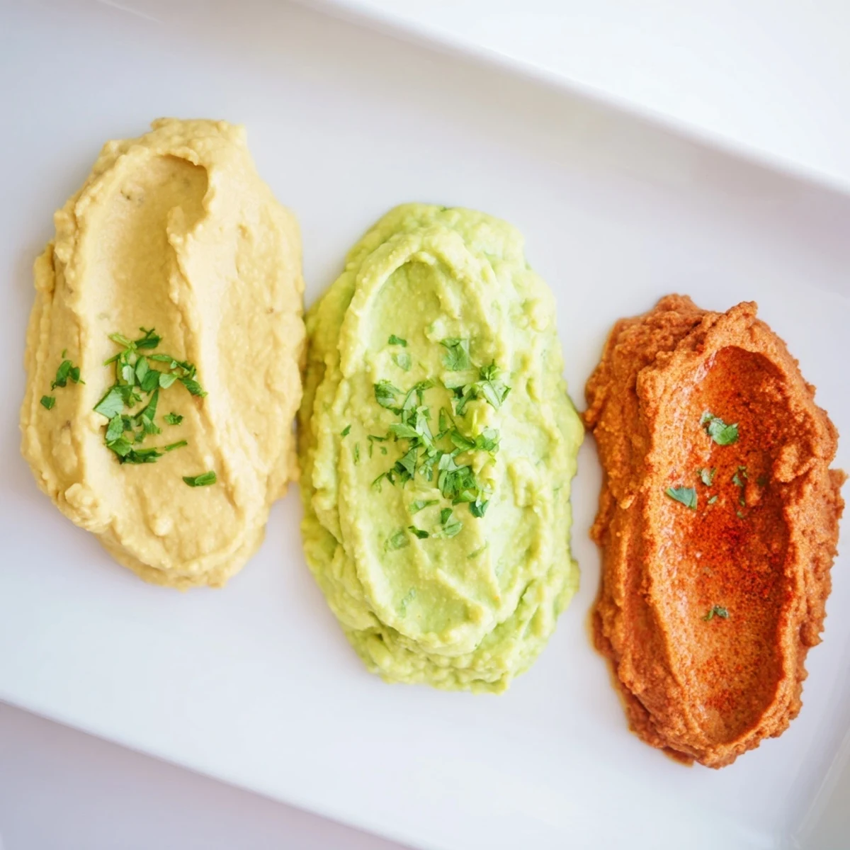 Beautiful and delicious Dip Trio, a perfect appetizer featuring vibrant hummus, and red and green dips for serving.