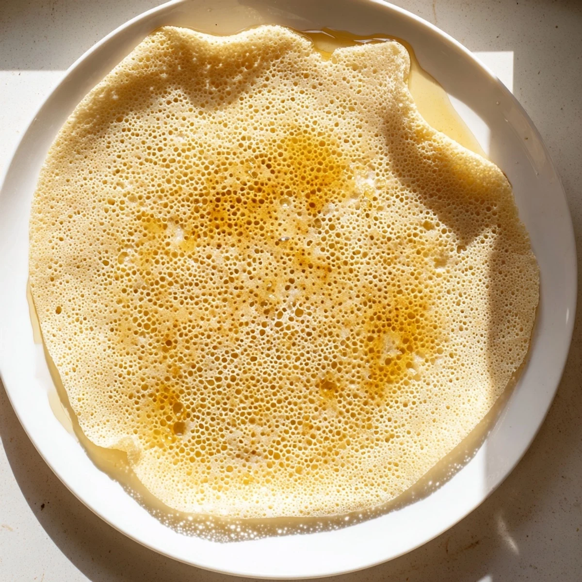 Fluffy Moroccan Baghrir crepes are soaked with honey butter, ready for a delicious breakfast.