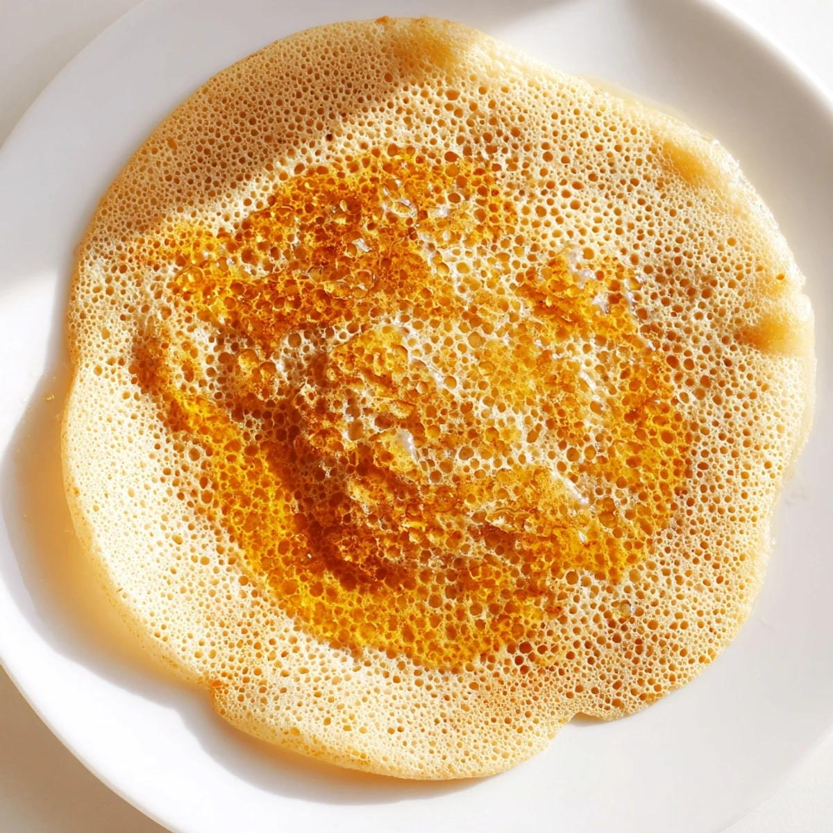 Close-up of freshly cooked Moroccan Baghrir, showcasing its airy texture, served with honey.