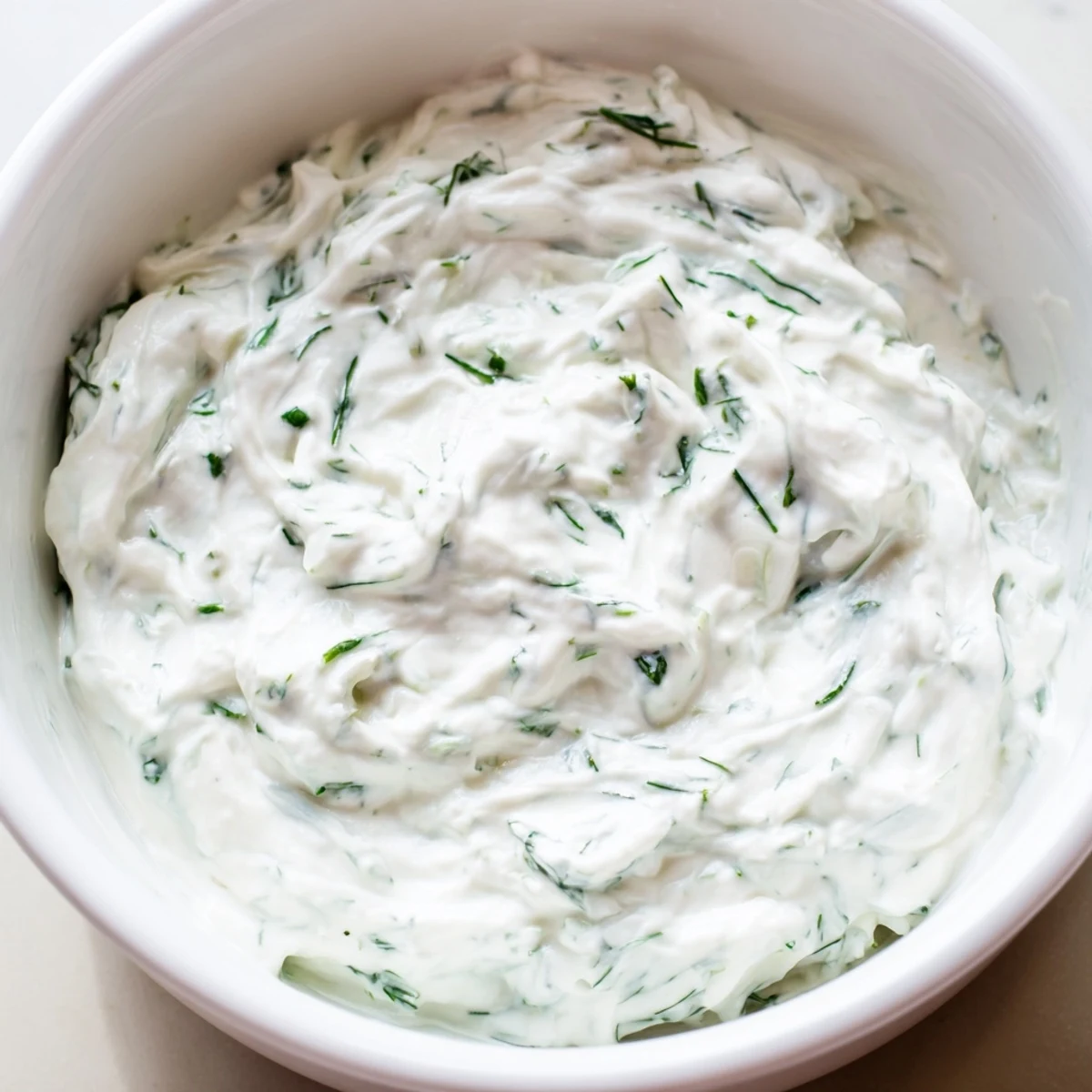 Creamy Greek Yogurt Herb Dip in a white bowl garnished with fresh dill, served with colorful vegetable crudités.  