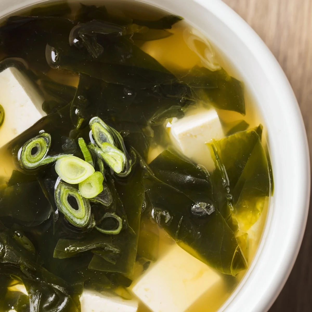 A comforting bowl of homemade wakame soup with silken tofu cubes and fresh scallions in a light broth.