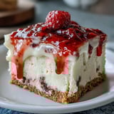 A rich slice of white chocolate raspberry cheesecake topped with vibrant raspberry sauce on a plate.