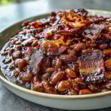1. Summer BBQ baked beans with brown sugar and bacon in a cast iron skillet, bubbling with sweet and smoky sauce.
