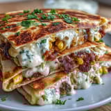 Golden-brown quesadillas stuffed with roasted corn, jalapeño, and Cotija cheese, drizzled with zesty chipotle crema for extra flavor.