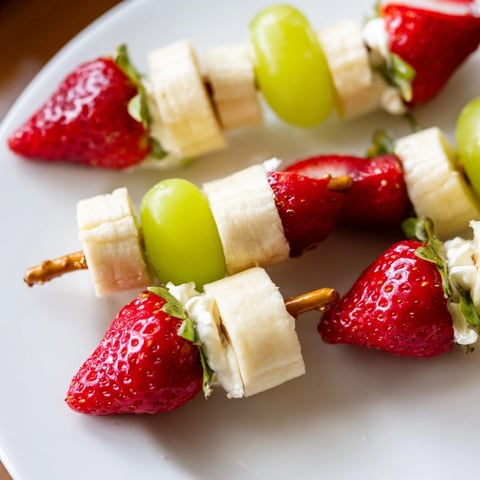 Vibrant Elf Hat Strawberry Skewers with red strawberries, banana hats, and green pom-poms for a joyful snack.