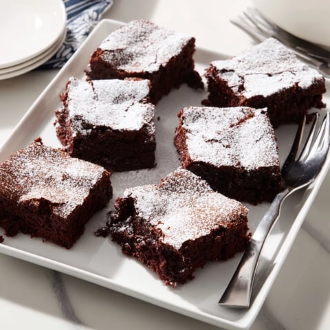 Fudgy, rich brownie squares, dusted with powdered sugar, ready for serving or enjoying.