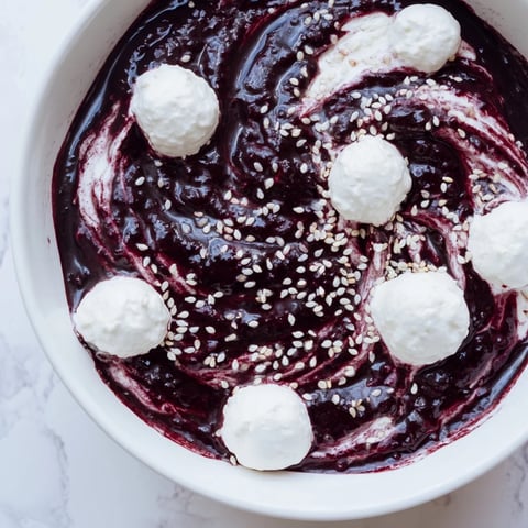 A vibrant The Galaxy Spiral dessert shows swirled berry jam on creamy yogurt, sprinkled with sesame stars.