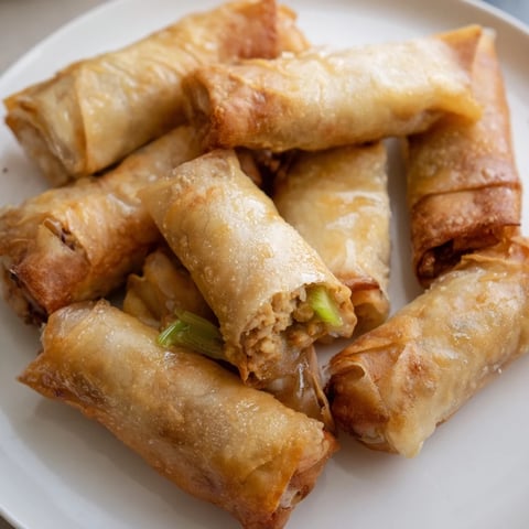 Golden-brown air fryer chicken lumpia bites, promising a crispy texture, ready for dipping.