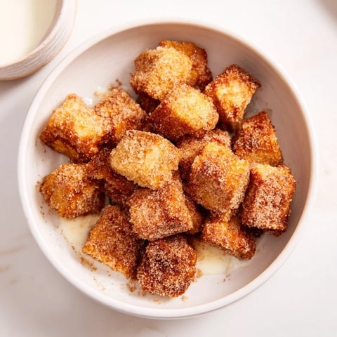 Golden, cinnamon-sugar coated French Toast Cereal, a breakfast treat ready to be enjoyed with milk.