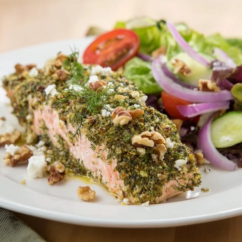 Flaky herb-crusted salmon salad, ready to eat, featuring bright greens and juicy tomatoes.