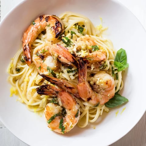 Steaming Lemon Herb Pasta with Shrimp, garnished with fresh herbs and lemon wedges adding brightness.