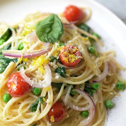 Spring Veggie One-Pot Spaghetti with peas, spinach, and cherry tomatoes steaming in a rustic ceramic bowl.
