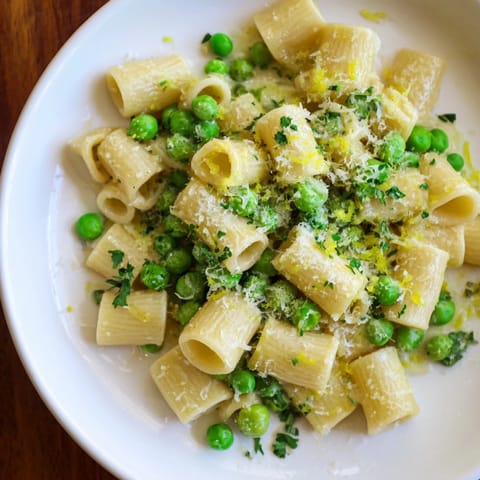 Close-up of golden Garlic Butter Ditalini with Peas, sprinkled with Parmesan cheese ready to eat.