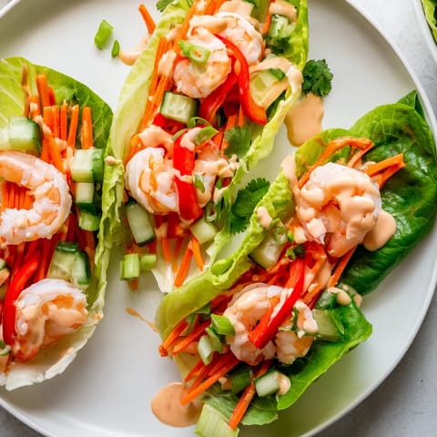 Freshly made shrimp lettuce cups, featuring tender shrimp, crunchy veggies, and a creamy, spicy sauce.