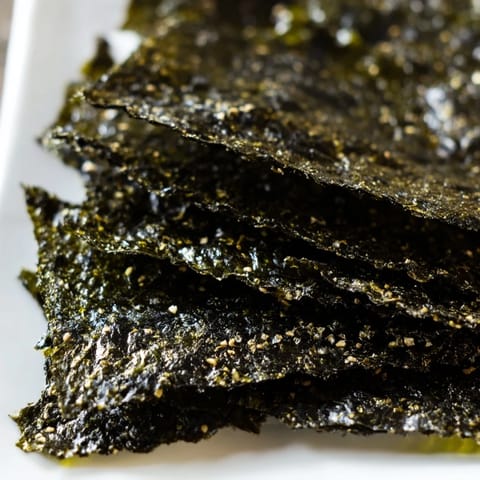 Close-up of crispy, oil-brushed roasted seaweed chips seasoned with sea salt.