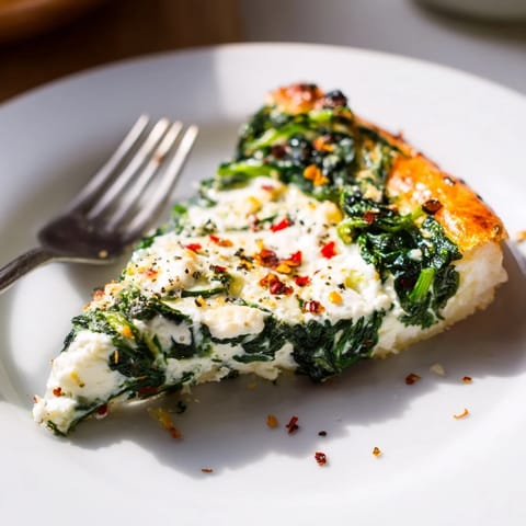 A close-up of a warm Spinach Ricotta Pizza slice, showing melted mozzarella and fresh herbs on a crisp, thin crust.