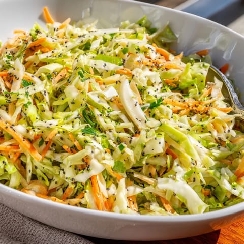 A vibrant bowl of Green Cabbage and Apple Slaw featuring julienned apples, green onions, and poppy seeds tossed in a creamy honey-mustard dressing.
