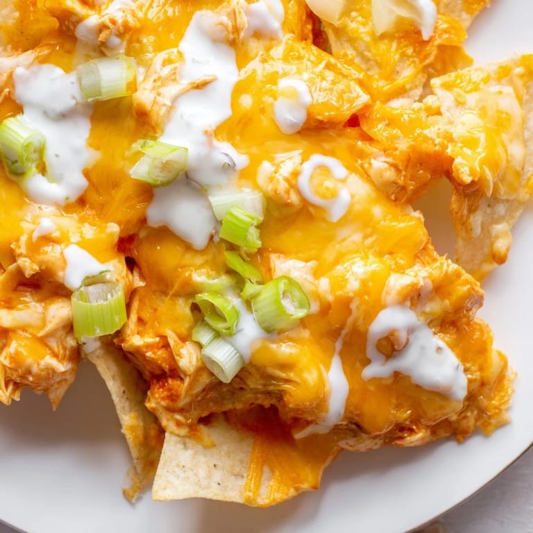An overhead view of bubbling Buffalo Chicken Nachos garnished with cilantro, ready to serve for game day with a side of ranch.
