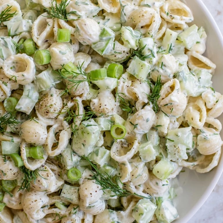 A close-up of vibrant green cucumbers, green onions, and dill mixed into the creamy Cucumber Crunch Pasta Salad.
