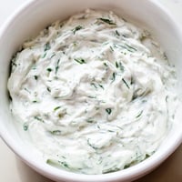 Creamy Greek Yogurt Herb Dip in a white bowl garnished with fresh dill, served with colorful vegetable crudités.  