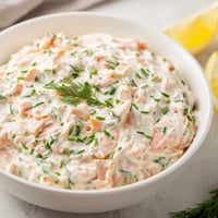 Creamy smoked salmon dip garnished with fresh dill and lemon wedges, served with crackers.  